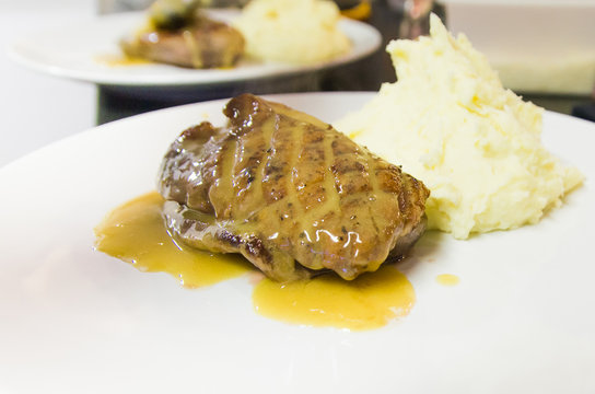 Duck breast with orange sauce on plate decorated with flowers.