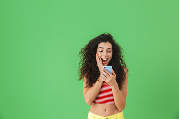 Photo of gorgeous woman smiling and using cell phone isolated over green background