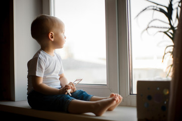 A little boy plays by the window with an airplane and dreams of flying.