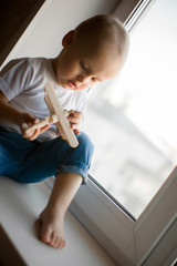 A little boy plays by the window with an airplane and dreams of flying.