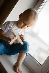 A little boy plays by the window with an airplane and dreams of flying.