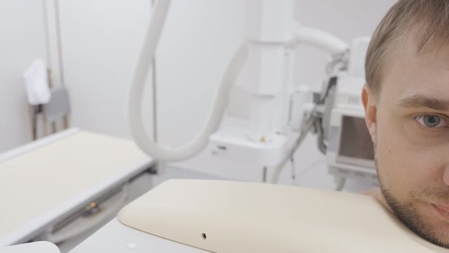 Radiologist operator preparation rontgen equipment for xray examine. Patient, waiting when machine detect the disease and doctor says a results. Close up young man face in the roentgen apparatus