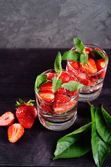 Detox infused water with strawberry and mint in sparkling glasses on wood table background, copy space. Cold summer drink. Mineral water