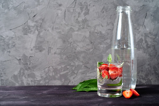 Detox Infused Water With Strawberry And Mint In Sparkling Glasses And Bottle On Wood Table Background, Copy Space. Cold Summer Drink. Mineral Water