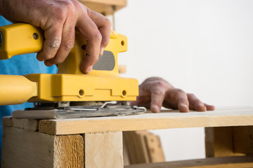 Hombre lijando un mueble de madera con una lija