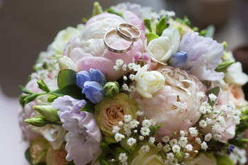 Wedding rings on a wedding bouquet of peonies and roses