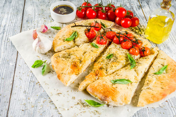 Traditional  homemade Italian flat bread focaccia. Focaccia with tomatoes and basil leaves, wooden background, top view