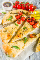 Traditional  homemade Italian flat bread focaccia. Focaccia with tomatoes and basil leaves, wooden background, top view