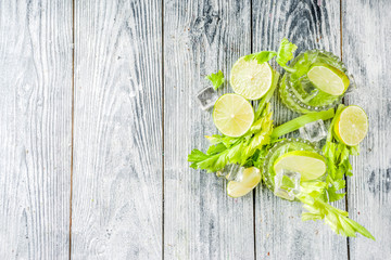 Celery Daisy Cocktail. Fresh summer drink, mojito, iced lemonade or margarita with celery and lime slices, wooden background copy space