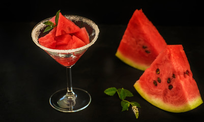 Slices of watermelon on a on black background and in a glass goblet, 