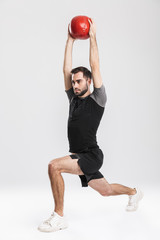 Young sports fitness man posing isolate over white wall background make exercises with ball.