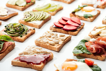 Toasts with cut fruits, fried eggs and peanuts on white