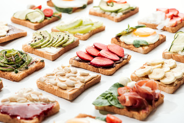 Toasts with cut fruits, fried egg and peanuts on white