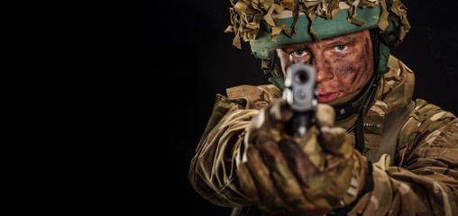 British soldier aiming with black pistol.