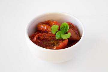 Sun-dried tomatoes in olive oil a white bowl with basil isalated on white background