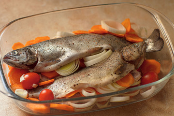 Fresh sea fish with spices and vegetable ingredients on wooden table, cooking concept.