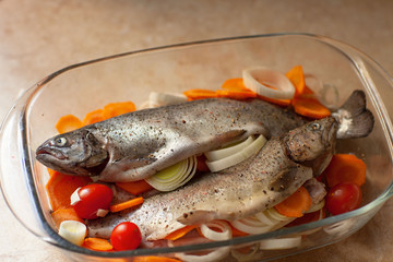 Fresh sea fish with spices and vegetable ingredients on wooden table, cooking concept.