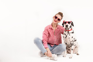 Portrait of happy young woman in good mood sitting with her dalmatian dog. Woman and pet in red...