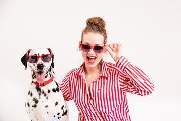 Portrait of happy young woman in good mood sitting with her dalmatian dog. Woman and pet in red...