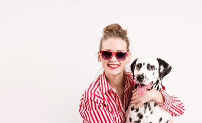 Portrait of happy young woman in good mood sitting with her dalmatian dog. Woman and pet in red...