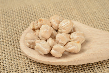 Garbanzos gordos en una cuchara de madera sobre fondo de tela, detalle