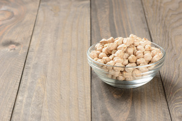 Garbanzos gordos en un cuenco de cristal sobre fondo de madera