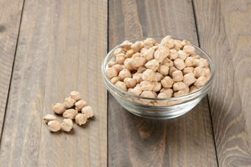Garbanzos gordos en un cuenco de cristal sobre fondo de madera