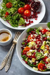 Healthy salad with tomatoes, feta, pomegranate seeds and leek.