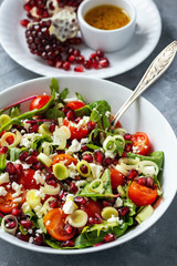 Healthy salad with tomatoes, feta, pomegranate seeds and leek.