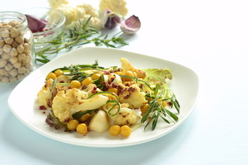 Roasted cauliflower with chickpeas, zucchini noodles and rosemary, salad, copy space