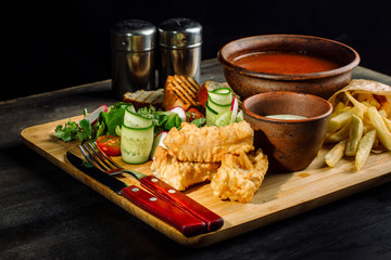 Lunch on a wooden board. Soup, chicken breast, salad and sauce.