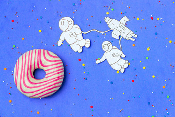 Creative Food Minimalism, Donut in Shape of Planet in Blue Sky with Astronaut, Space Ship Top View, Copy Space.