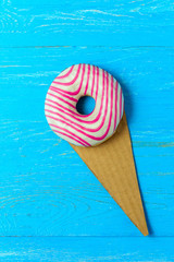 Creative Food Minimalism, Donut in Shape of Ice Cream on Blue Table. Top View, Copy Space.