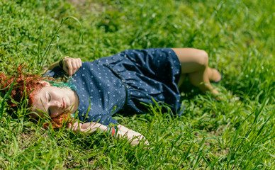 Fototapeta premium Beautiful redhead girl lay on grass.