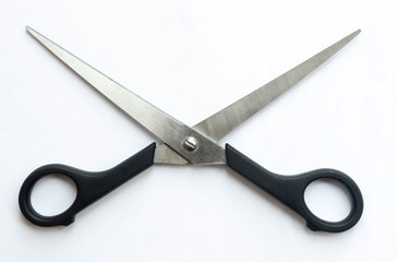 A pair of sharp metal cutting scissors with the cutting blades open. scissors for craft isolated against a white background. Black handle.