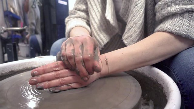 Woman shaping pottery on potter's wheel.