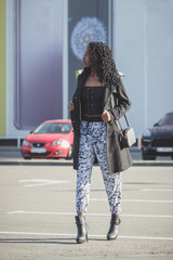 Young woman dressed in casual clothes walking on the street, soft focus background