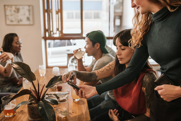 Customer paying the bill with her smartphone in a bistro