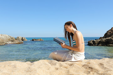 Tourist on the beach reading a paper book in summer