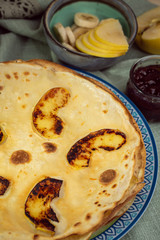 Cooked crepes folded on a plate with jam and apples