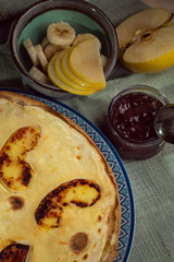 Cooked crepes folded on a plate with jam and apples