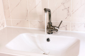 Faucet pouring water into white sink