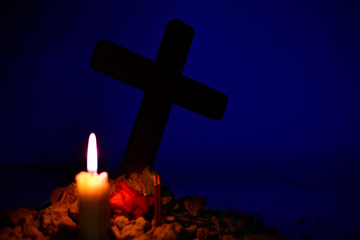 Giving respect to human soul. Give a candle and rose under Jesus cross in cemetery on moonlight.