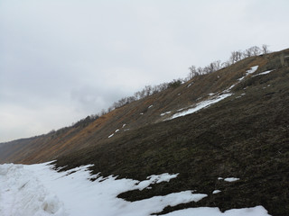 Russian landscape with hills in the melting forest in early spring