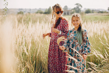 Fashionable mother with daughter. Family in a summer fiels. Girl in a red dress.