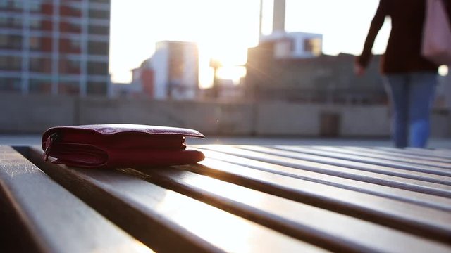 Lost wallet. Woman is leaving from a bench where she forgot her wallet