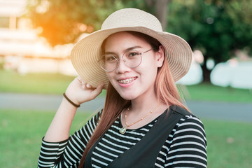 Portrait of sexy beautiful asian thai girl women wear glasses and braces wearing a hat take a selfie portrait with her smartphone in garden.