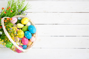 Basket with easter eggs on rustic wooden table. Top view.