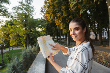 Smiling young girl tourist analyzing city map