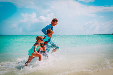 father with kids play with water run on beach